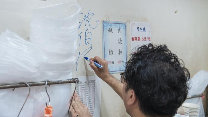民進黨台北市長參選人沈伯洋簽名在東發號牆上,但店家事後不堪出征,將台北市長蔣萬安、沈伯洋的簽名都塗銷。(圖/沈伯洋競辦提供)