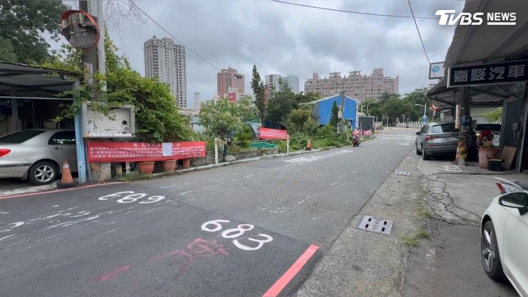 路面掛上紅布條,地號「683」範圍,包含兩旁鐵皮屋及工務局租賃之柏油道路,工務局強調仍屬租賃期間,地主無法自行收回。(圖/TVBS)