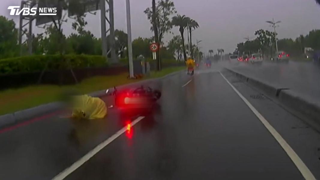 高雄小港暴雨釀災,騎士小心翼翼閃過積水處,一輛轎車快速通過,疑遭轎車濺水摔倒。(圖/TVBS)
