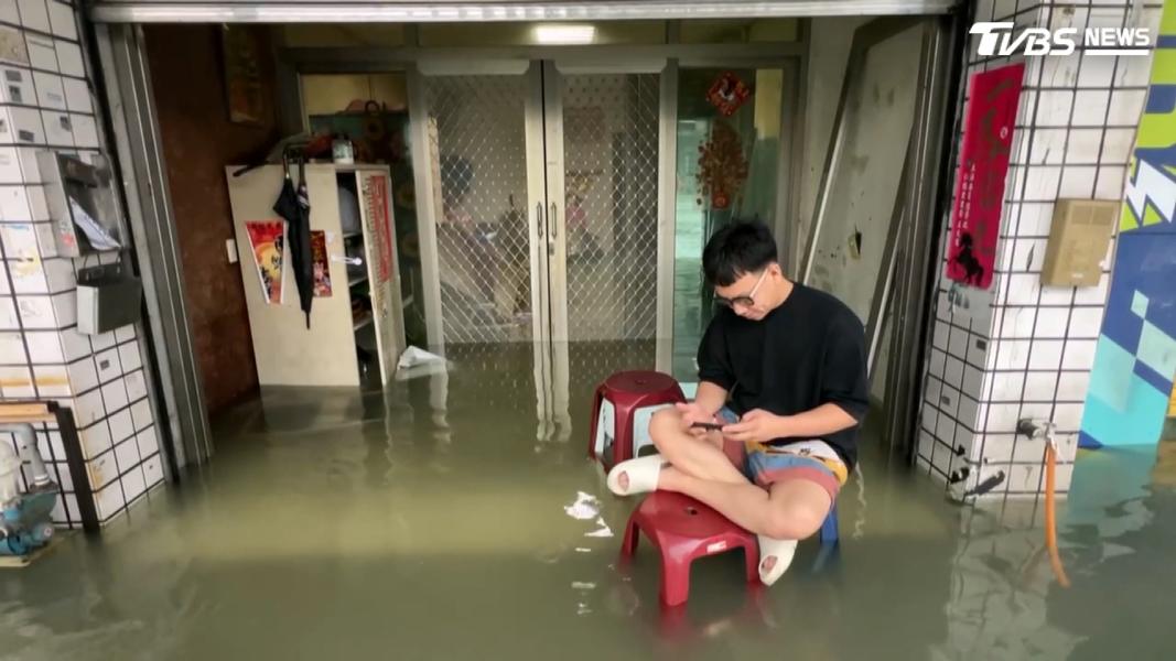 面對泥水淹進家裡,民眾索性放棄清掃,搬出塑膠椅坐在家門口等待積水消退。(圖/TVBS)