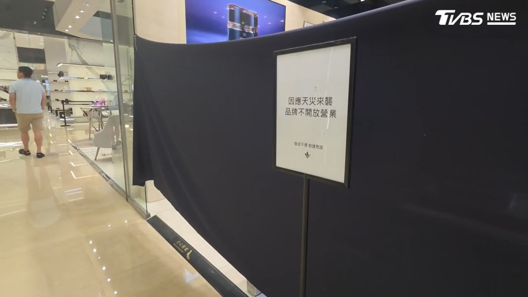 沒營業的品牌有的蓋上黑布,有的拉起紅龍、擺出因天災來襲,品牌暫不開放的告示牌,讓一早冒雨上班的其他櫃姐好羨慕(圖/TVBS)