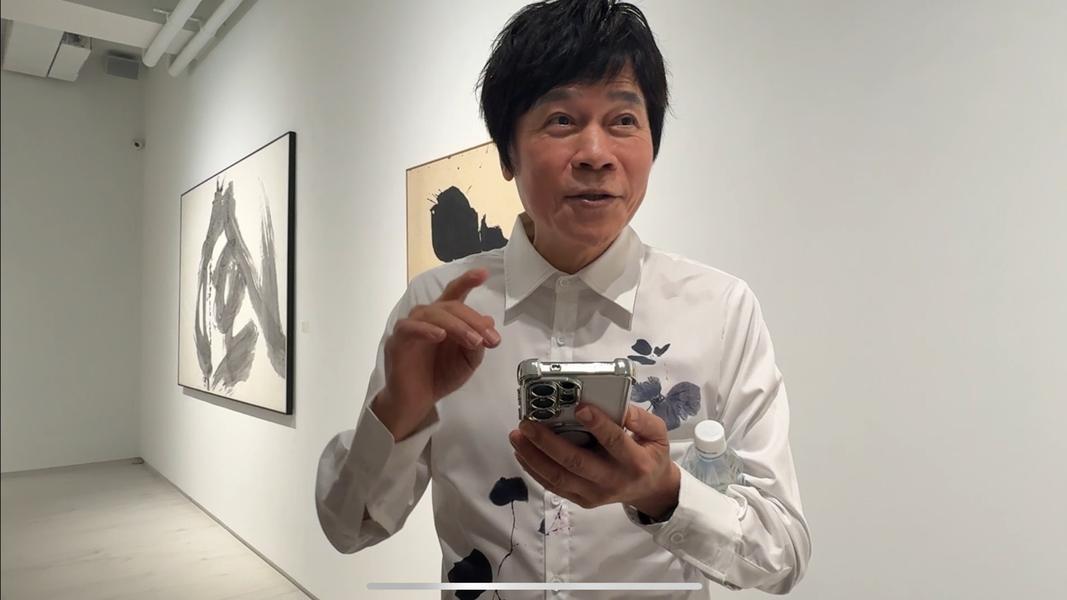 洪榮宏邊滑手機邊受訪。(圖/黃盈容攝)