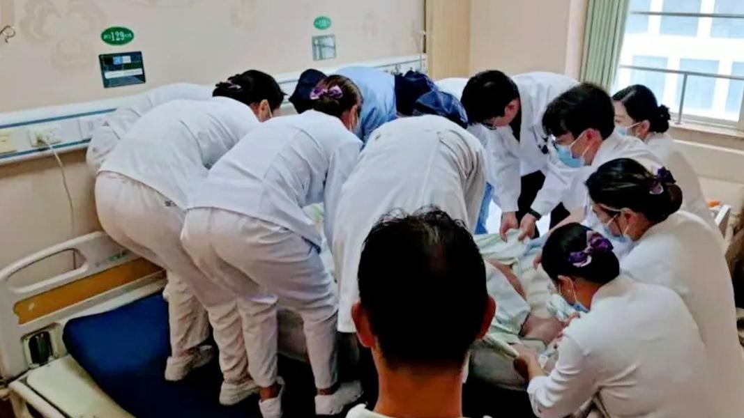 院方出動12名醫護人員,才將他搬運至特製病床上。(圖/翻攝自深圳衛視)