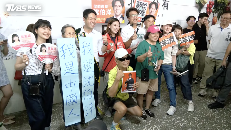 有民眾手持「我是中國人,我選沈伯洋」標語找民進黨台北市長參選人沈伯洋合影。(圖/共訊畫面)