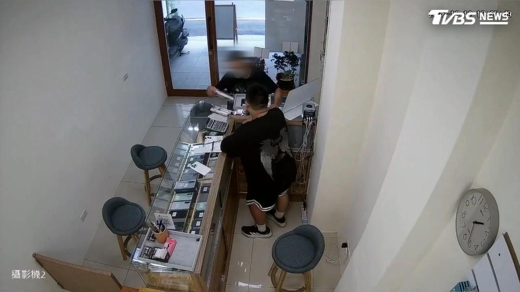 身穿黑衣牛仔褲的男子站在通訊行櫃台前,比劃著要購買手機殼和保護貼,趁店員轉身到倉庫拿取商品時,拿起早已鎖定的2支手機拔腿狂奔(圖/TVBS)