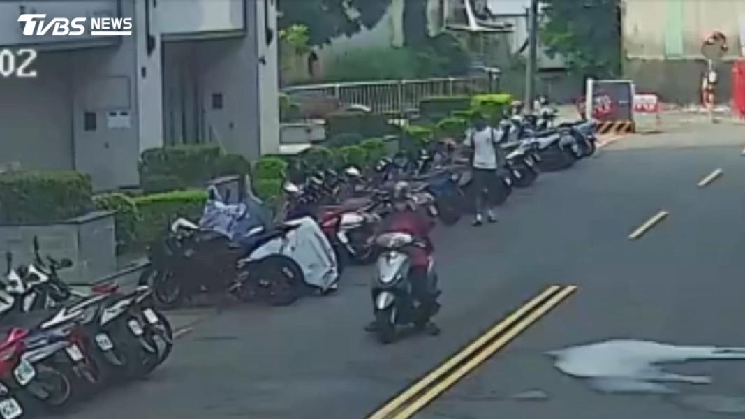 林男身穿白衣對整排停放在路邊的機車下手。(圖/TVBS)