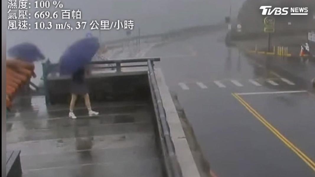 南投武嶺兩名遊客原本撐傘行走,一走上地標武嶺亭,其中一名女子的雨傘馬上開花。(圖/翻攝網路)