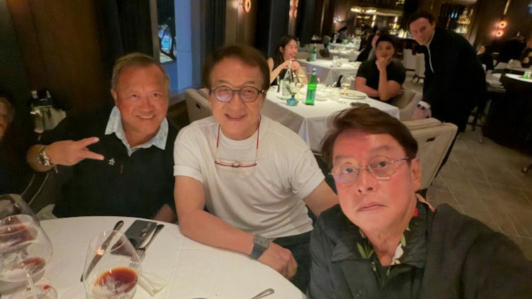 成龍(中)穿著簡約白色T恤、戴著眼鏡,與多年好友碰杯聊天。(圖/翻攝自譚詠麟微博)
