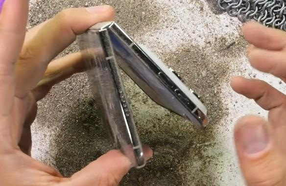 沙塵疑似滲入轉軸縫隙,導致轉軸運作卡死,手機無法順利闔上。(圖/翻攝自YouTube@JerryRigEverything)