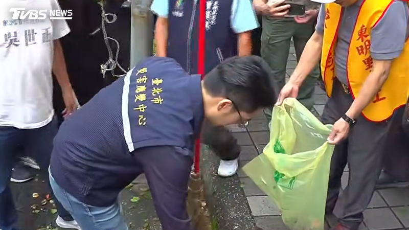台北市長蔣萬安視察南港東明公園,單手拿起掃帚掃落葉。(圖/TVBS)