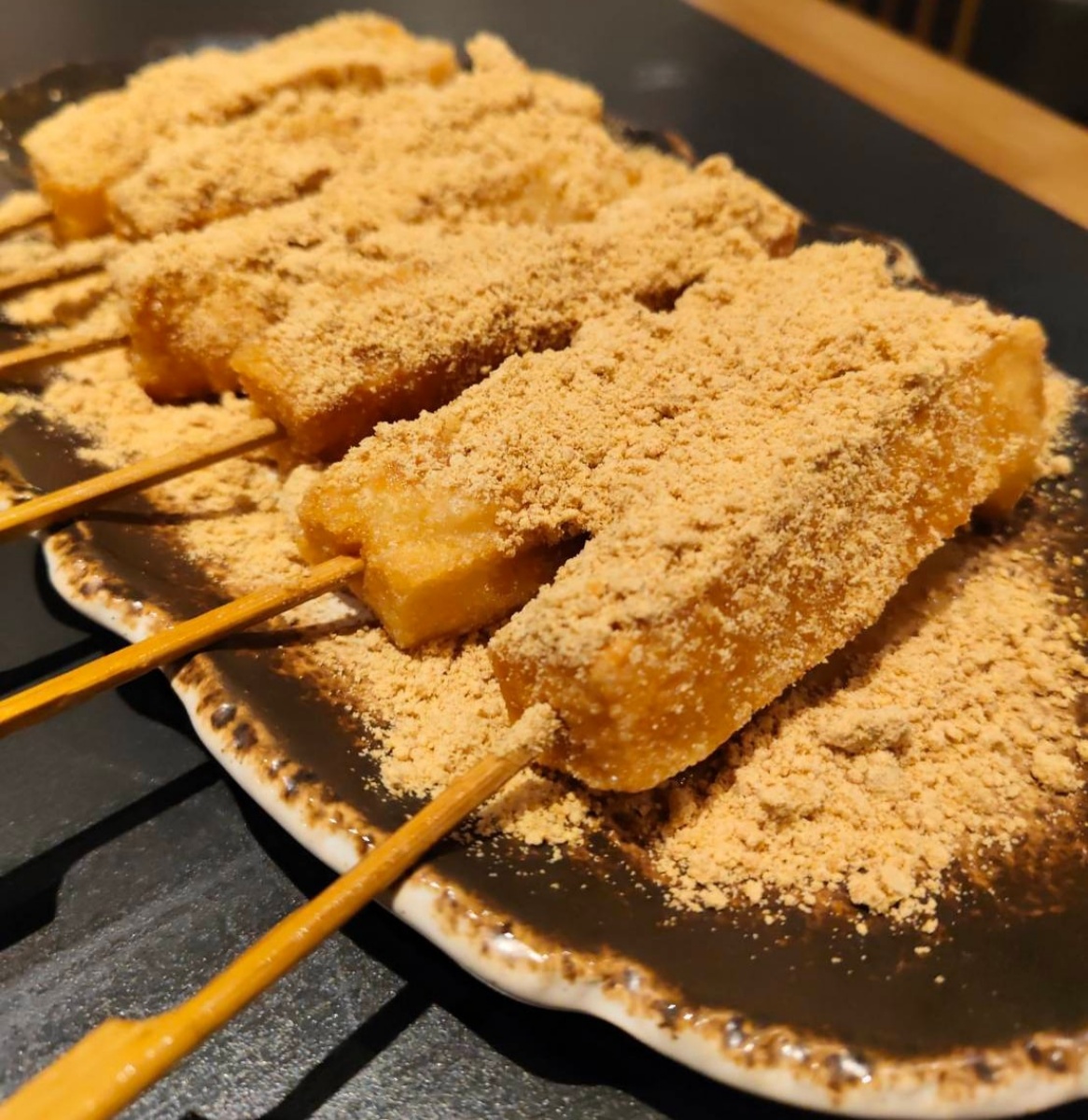 「紅糖糍粑串」(100元,小份、160元,大份)口感就像沾滿紅糖與花生粉的煎年糕,香甜滋味很討喜。(圖/舒愛吃愛玩樂的世界提供)