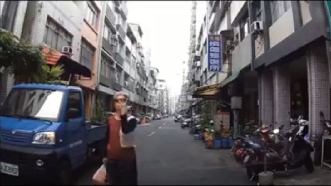 一名戴著墨鏡的白髮阿嬤,站在路中央不走,還接連比出奇怪手勢。(圖/翻攝自爆料公社臉書粉絲團)