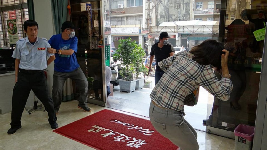一名假扮的歹徒控制住保全,另名則持槍查看面動靜。圖/翻攝自台南市政府警察局第五分局治安、交通、服務宣導團臉書