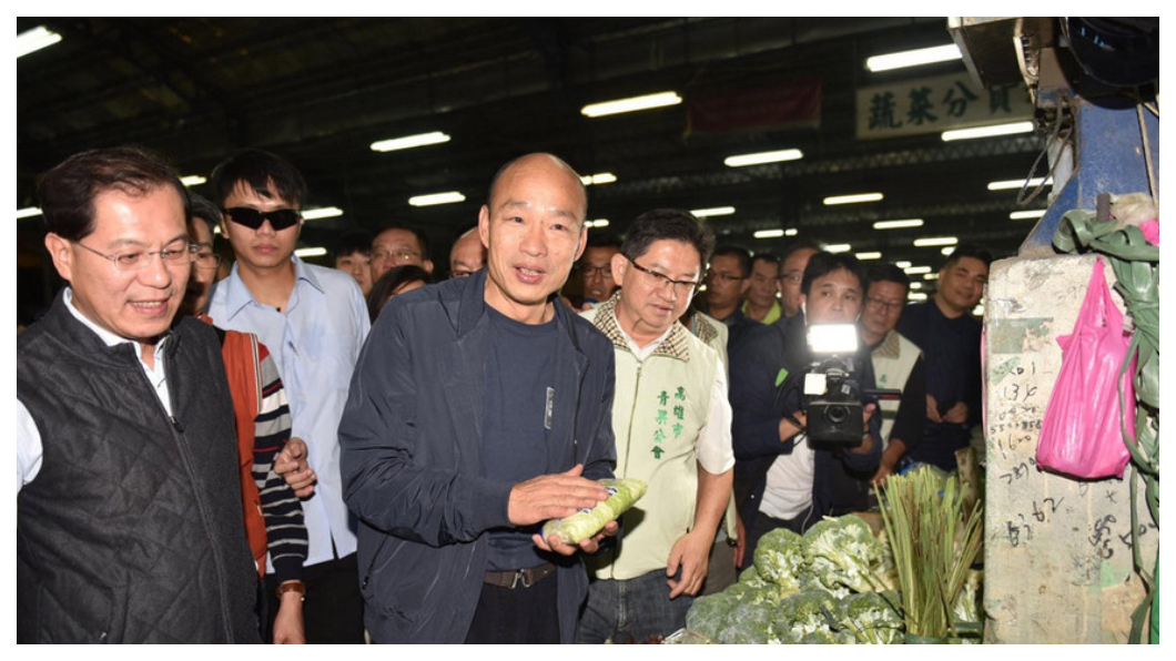 高雄市長走馬上任第一天，韓國瑜(左三)夜宿高雄十全果菜市場，緊跟在旁、邊聽邊做筆記的人，是高雄新任農業局長吳芳銘(左一)。距離他們宣布就任新職的時間還不到24小時，他們隨時已在掌握攤商心聲、農產運銷「價」與「量」的供需。   圖／中央社