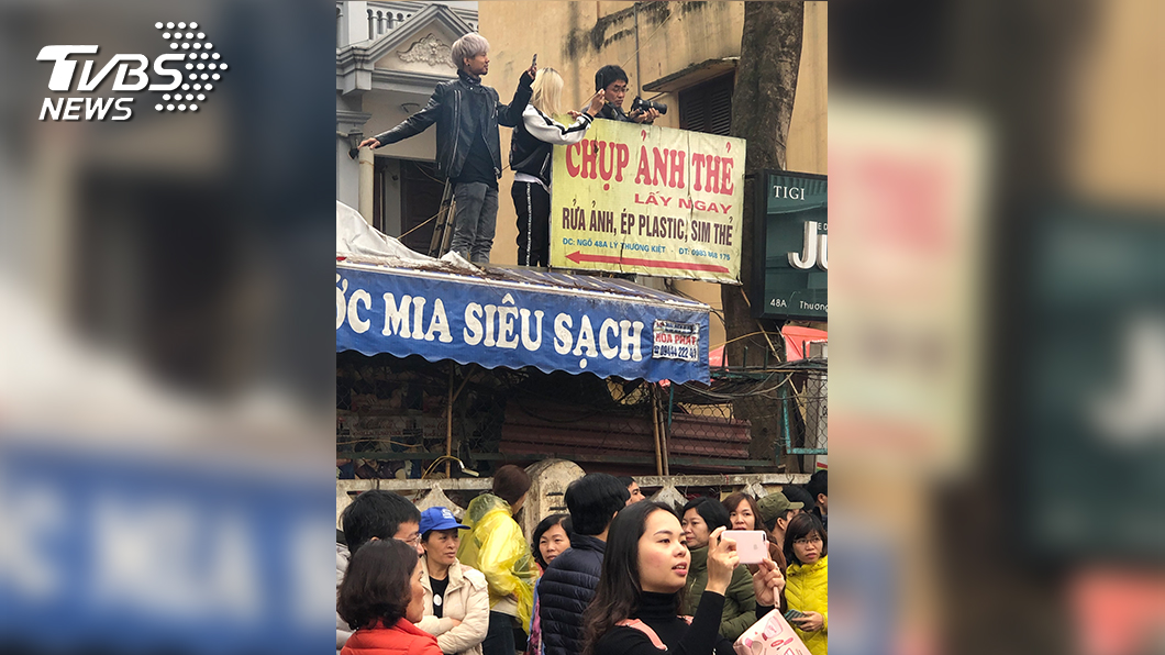 當地居民為了一睹這場國際盛事，不惜爬到屋簷上觀看和拍照。（圖／TVBS）