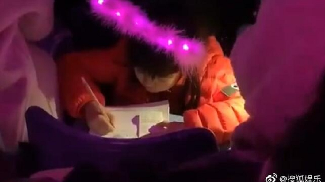 周杰倫在台上高唱,台下卻有小妹妹趴著專心寫作業,畫面感十分衝突。(圖/翻攝自微博)