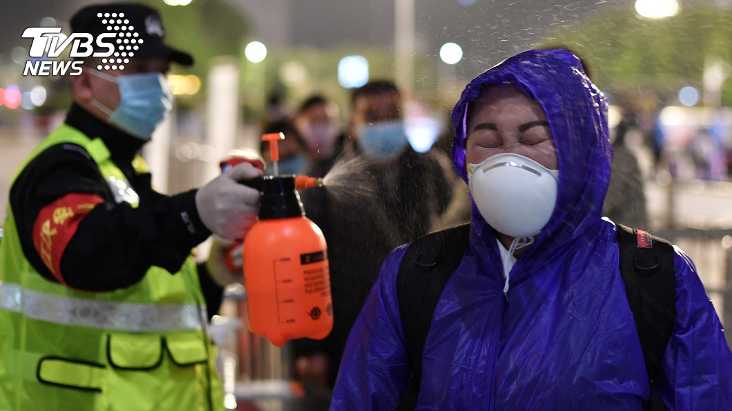警方幫漢口火車站旅客噴灑消毒劑。(圖/達志影像路透社)