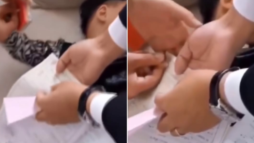小朋友在睡夢中被家人拉小手捺手印。(圖/翻攝自微博)