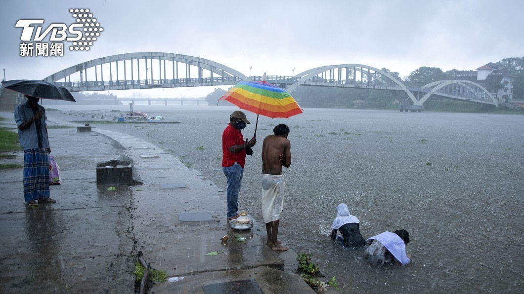 病歿者家屬冒著風雨,在河中為過世的親人舉辦送別儀式(圖/達志影像美聯社)