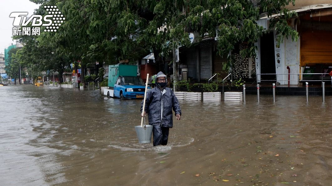 孟買民眾穿戴著雨衣、口罩在風雨中做好防疫措施(圖/達志影像美聯社)