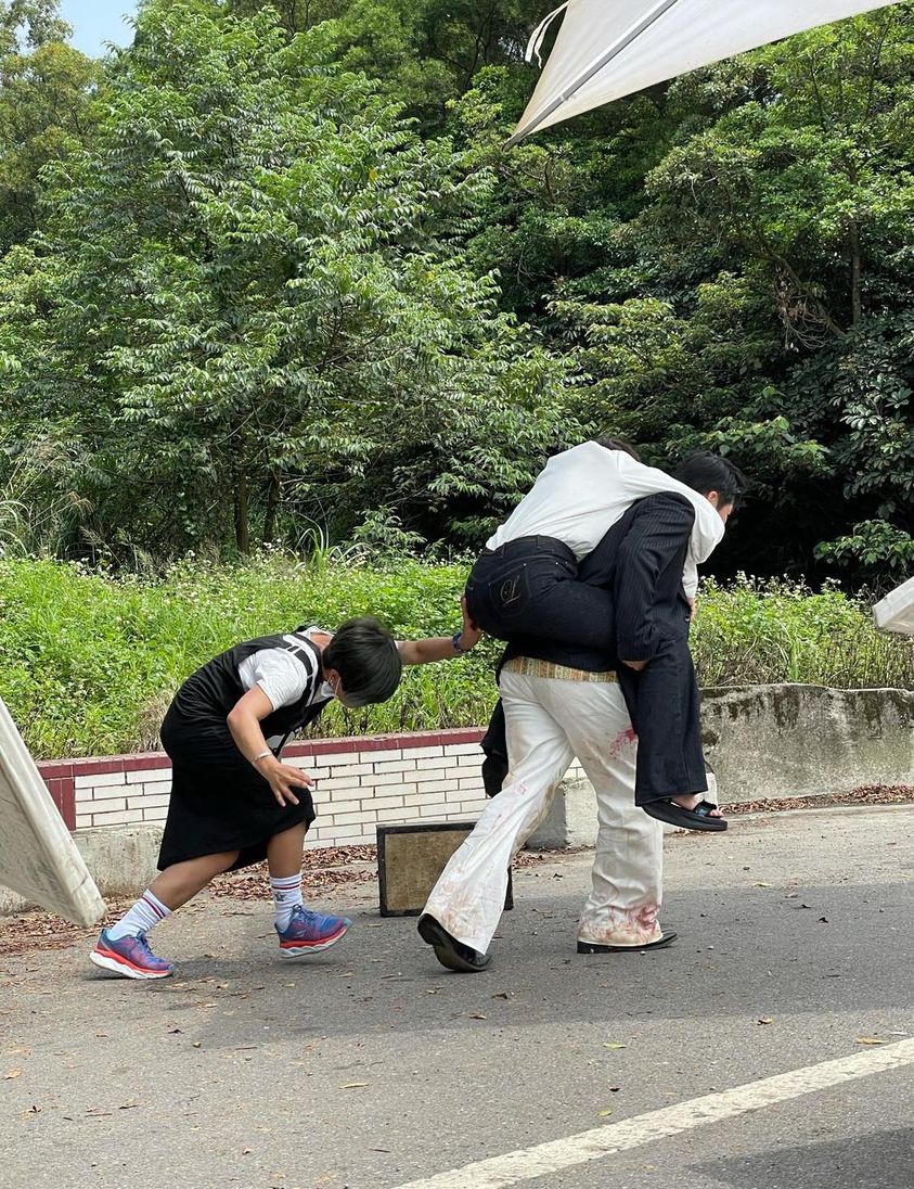 陳美鳳在片場被洪都拉斯背著,副導在一旁幫忙推一把。(圖/翻攝自陳美鳳臉書)