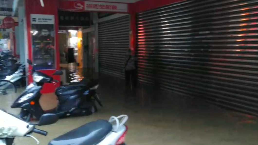 吳興街水淹上騎樓,阿嬤扶牆緩慢前行。(圖/讀者提供)