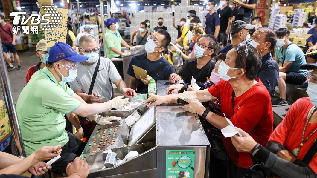 台北第一果菜批發市場照常開市,北農員工及承銷商戴口罩進行拍賣。(圖/中央社)
