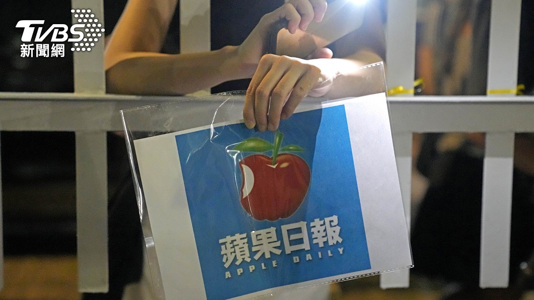 讀者拿著香港蘋果日報的報頭,來到報社總部門外。(圖/達志影像美聯社)