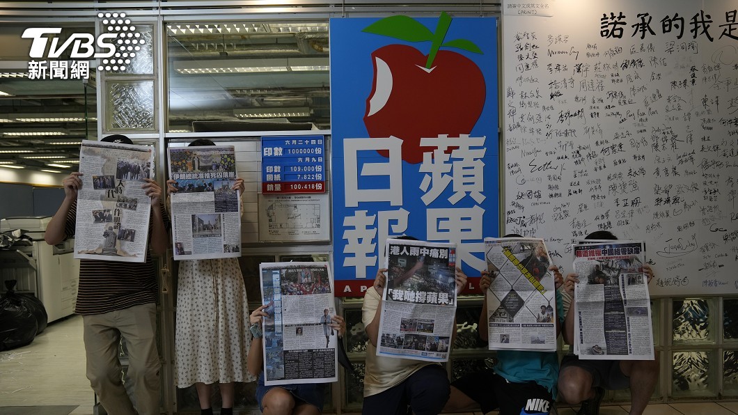 員工拿著剛出刊的最後一期報紙,在報社門口合照留念。(圖/達志影像美聯社)