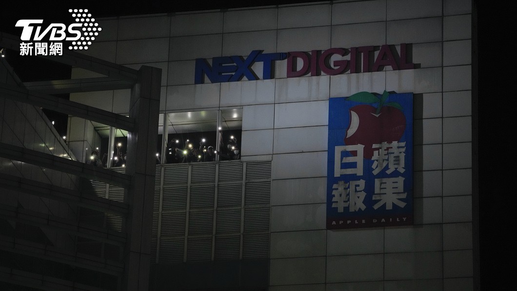 工作人員在辦公室裡透過手機燈光對來到報社外的讀者表示感謝。(圖/達志影像美聯社)