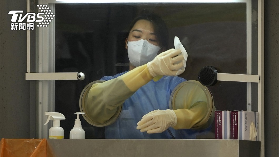 醫務人員完成檢測工作後,拿著酒精布擦拭隔板。(圖/達志影像美聯社)