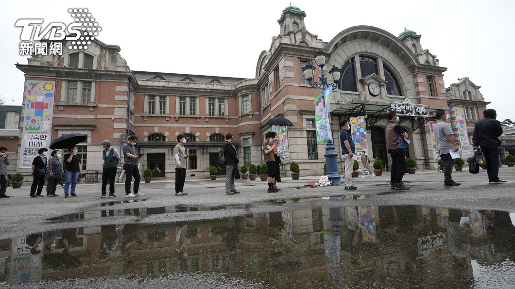 等待接受檢測的排隊民眾,自動拉開間隔距離,落實防疫要求。(圖/達志影像美聯社)