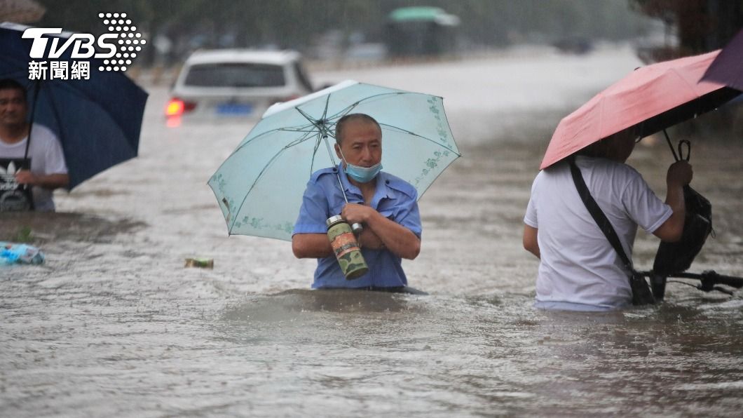 行人抱著個人物品涉水行經在街道上。(圖/達志影像路透社)
