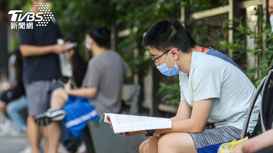 考生在進考場前拿出課本講義複習，做最後衝刺。（圖／中央社）