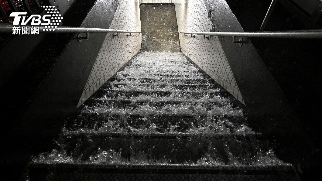 大雨排水不及,自地鐵入口灌入。(圖/AP)