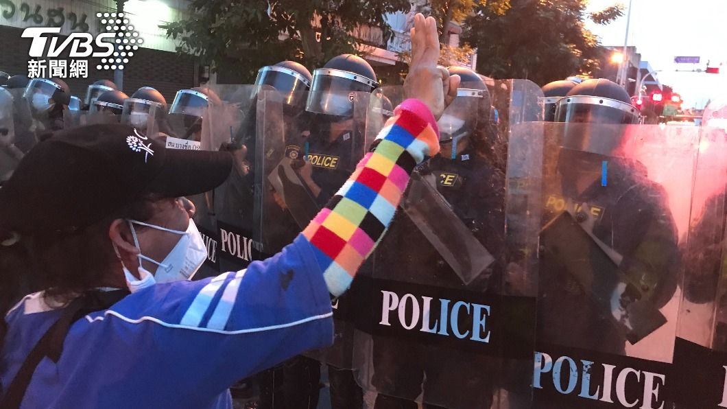 抗議民眾對著鎮暴警察高比象徵反政府的三根手指手勢。（圖／中央社）