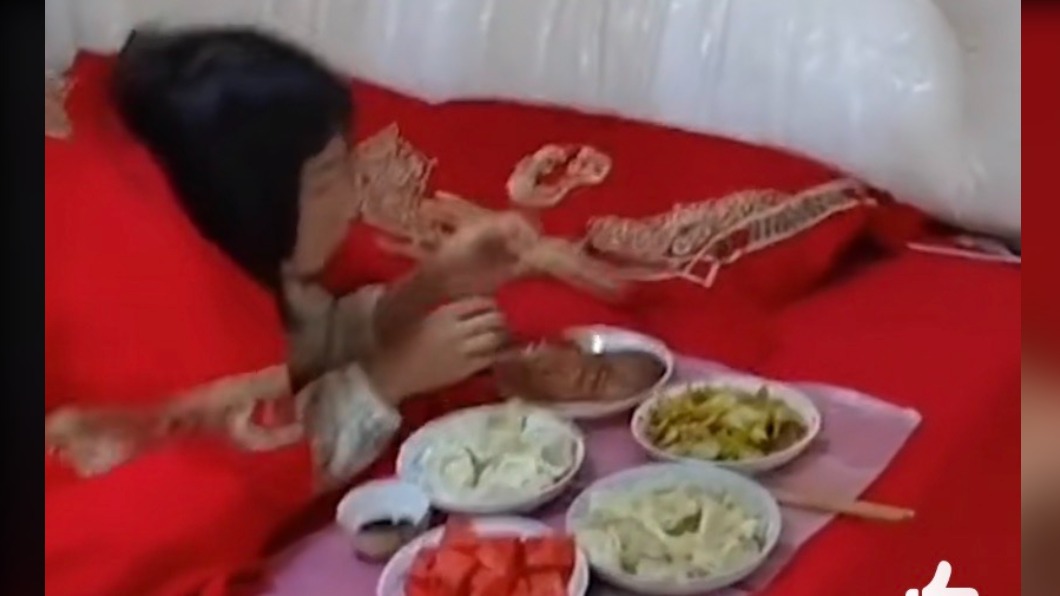女子躺在床上吃飯。(圖/翻攝自微博)