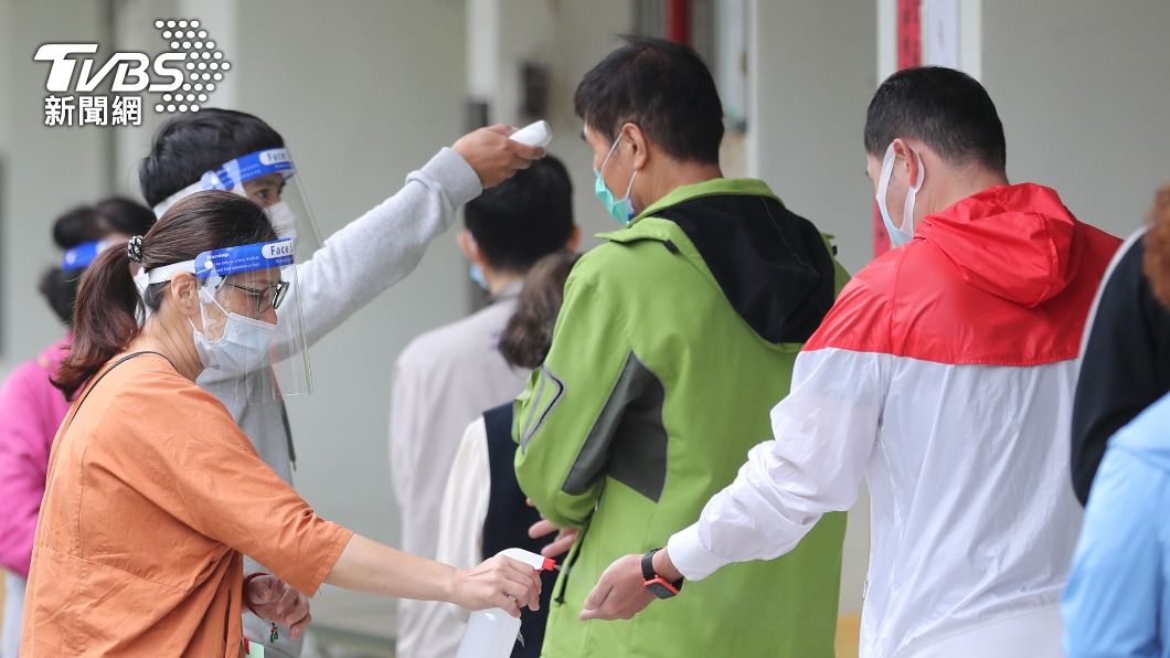 民眾進入投票所前,先由工作人員量測體溫、噴酒精消毒手部。(圖/中央社)