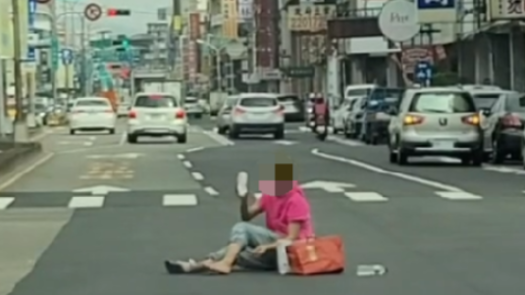 跳舞哥不管車流量,曾坐在街口拿水瓶灑水。(圖/翻攝自記者爆料網)