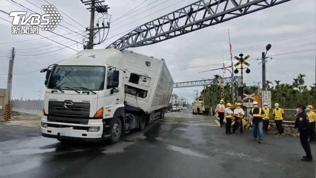 貨櫃車撞歪限高門,卡在平交道上,警方及工務維修人員前往處理。(圖/TVBS)