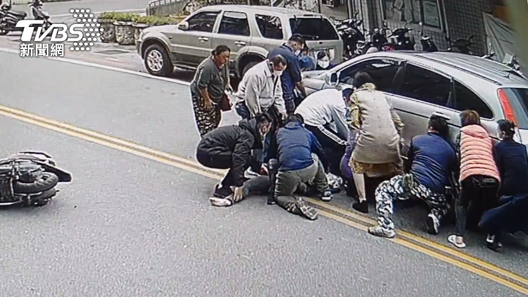 一名女騎士卡在轎車車底，民眾合力將車抬起，試圖將人救出。（圖／讀者提供）