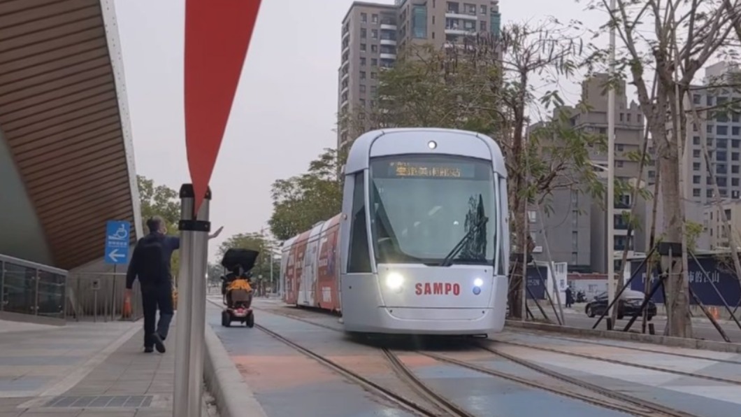 阿伯騎電動代步車與輕軌併排行駛，民眾好心示意提醒。（圖／翻攝自網路）
