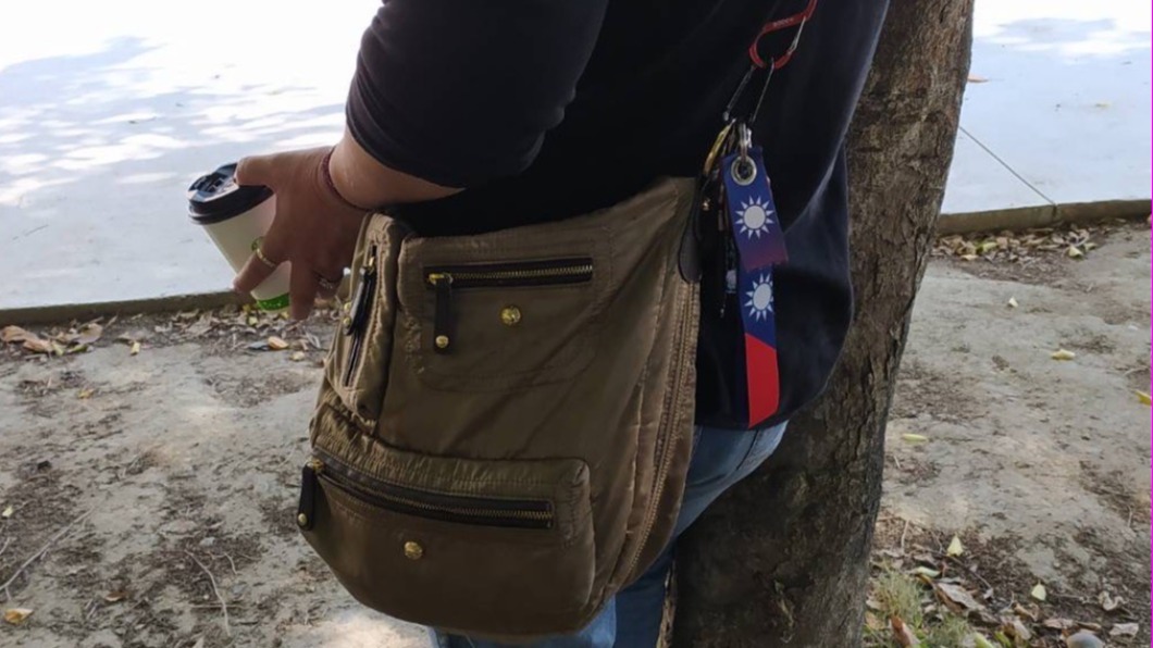 台中市第二選區補選,一名婦人持咖啡杯針孔攝影機在投票所外拍攝。(圖/林靜儀競總提供)