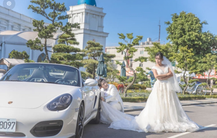 照片中陳伶宣老公拿起新娘裙擺去擦保時捷跑車的輪圈，而陳伶宣本人則是雙手抱胸露出不悅表情。（圖片來源／陳伶宣FB）