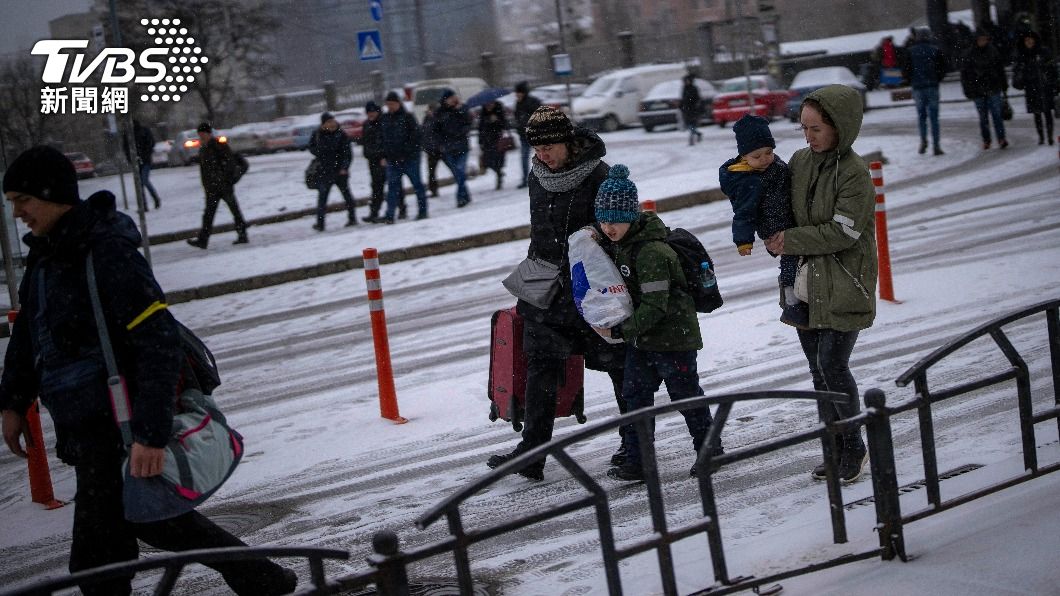 烏俄戰事進入第6天，基輔市民戴著簡單家當，在雪中步行前往火車站。（圖／達志影像美聯社）