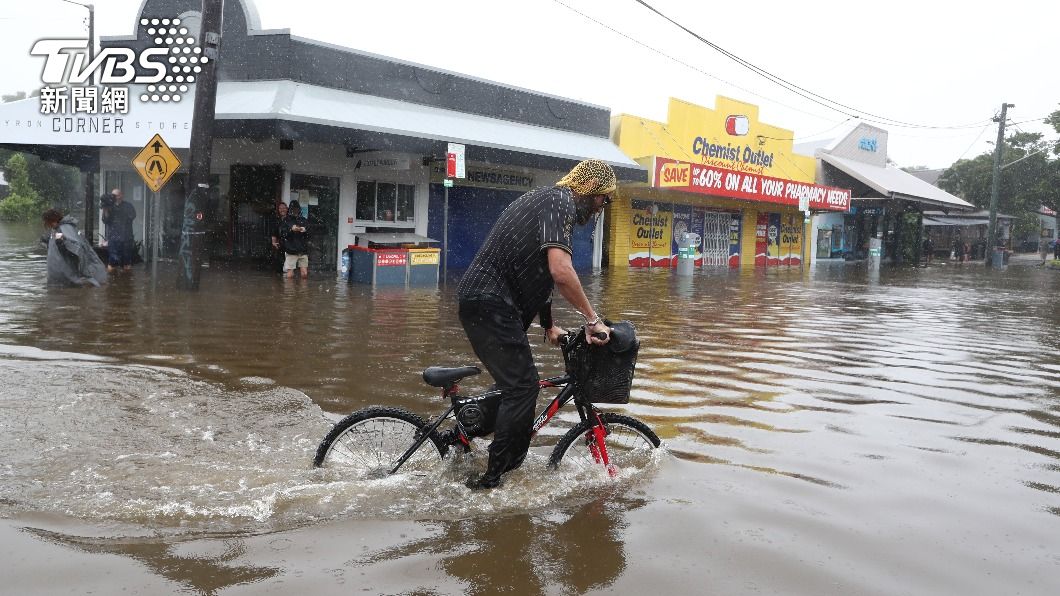 民眾奮力騎著腳踏車穿越積水區。(圖/達志影像歐新社)