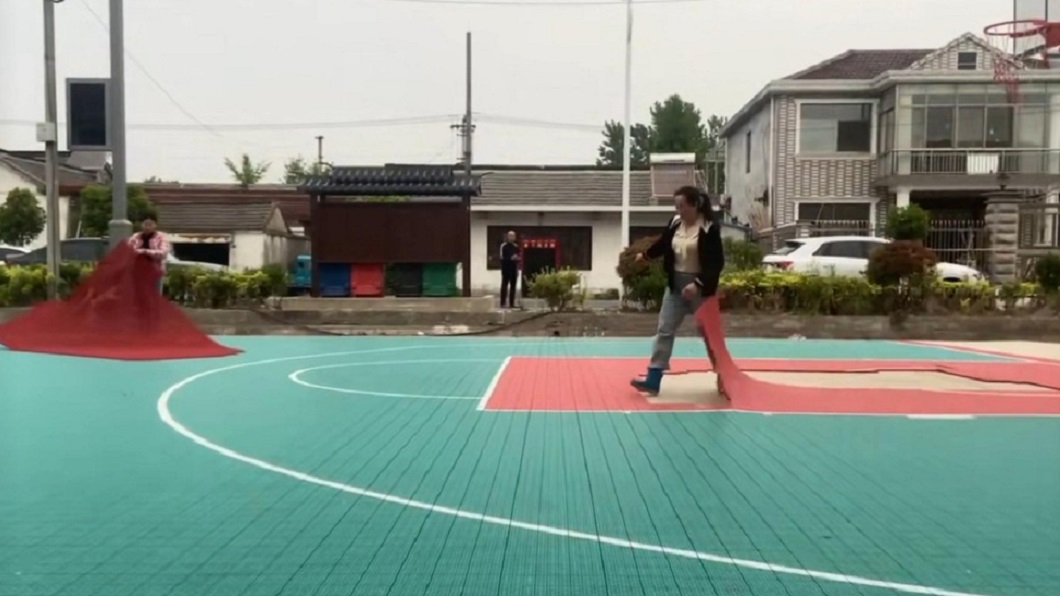 婦人一氣之下把籃球場地皮撕開。(圖/翻攝自網易新聞)