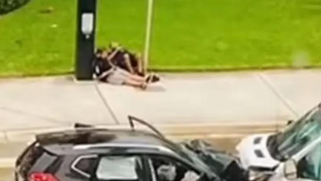 貨運卡車上的工作人員僅受到輕傷,坐在路邊等警方處理車禍。(圖/翻攝自《紐約郵報》)
