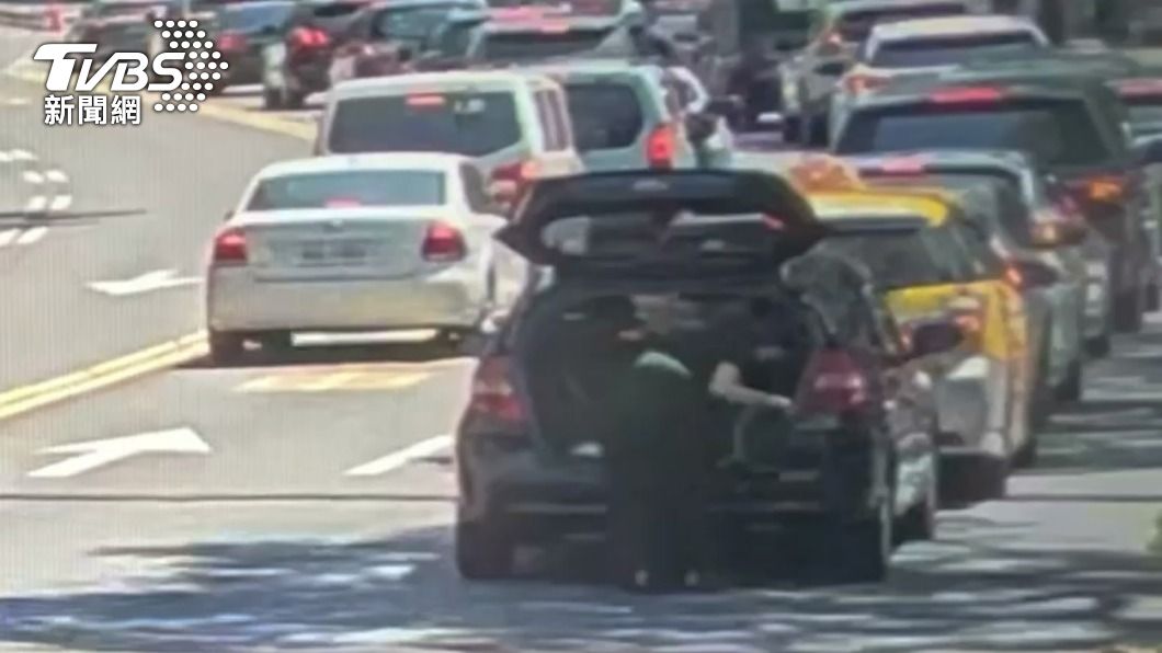 女駕駛等紅燈時下車到後車廂拿東西。(圖/TVBS)