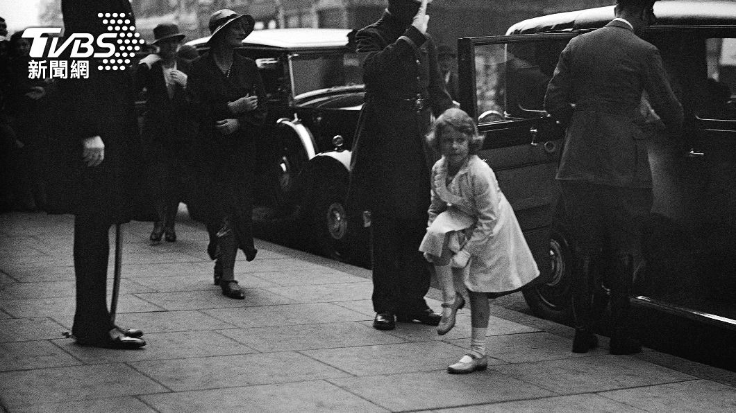 1933年,年僅7歲的伊莉莎白二世尚未成為王位繼承人,下車後站在路邊用手拉起襪子。(圖/達志影像美聯社)